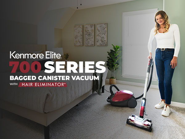 Woman using Kenmore Elite 700 Series bagged canister vacuum in a living room.