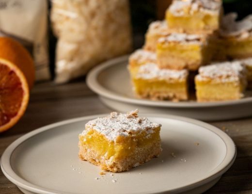 A slice of yellow dessert on a plate, with more pieces in the background.