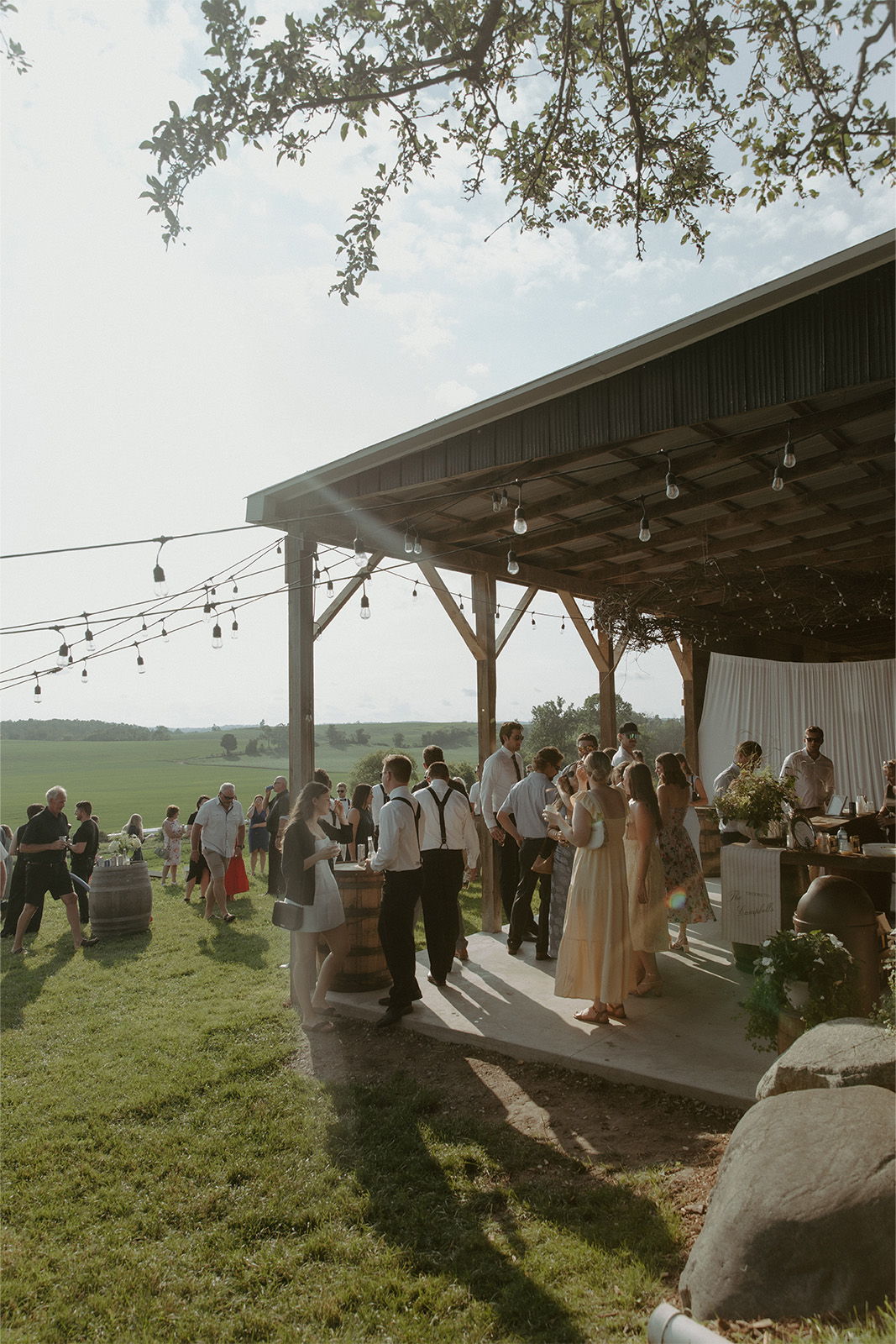 Outdoor gathering at a rustic venue with people mingling and enjoying the event.