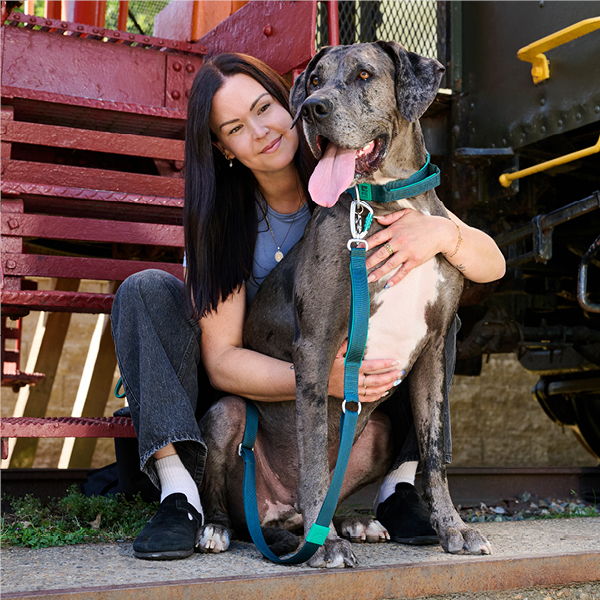 Woman sitting with a large dog, both smiling outdoors.