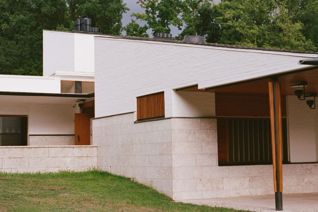 Modern architectural building with white walls and wooden accents. Green surroundings.