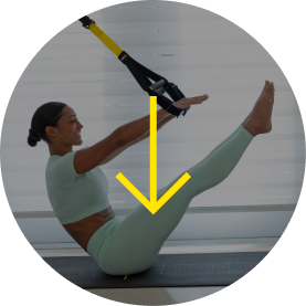 Woman exercising with TRX straps in a bright room.