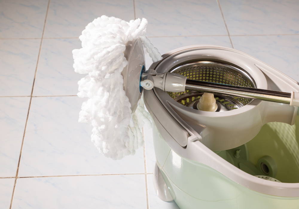 spin mop leaning on top of a beige colored spin bucket