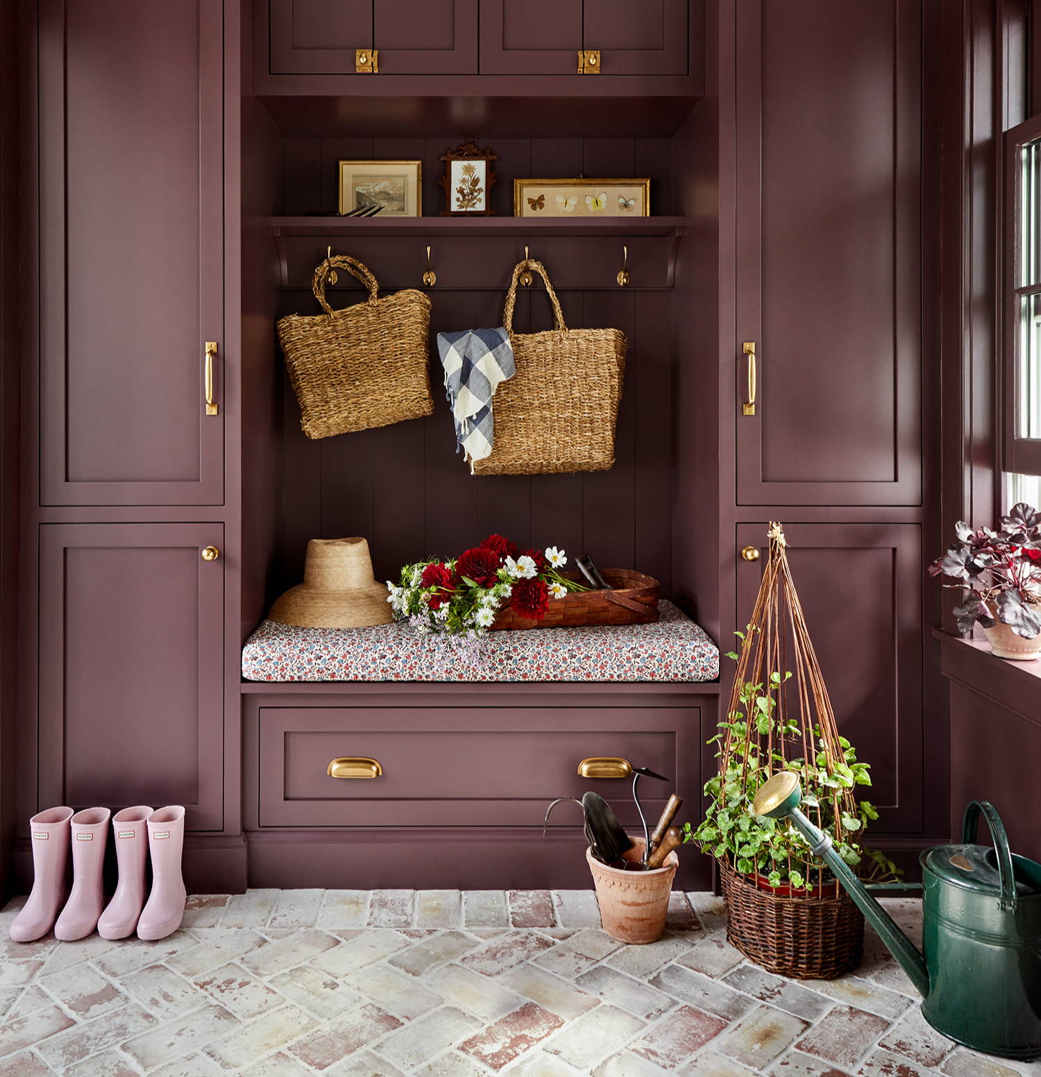 Luxury mudroom design by Jennifer Hunter with plum cabinetry, brass hardware and brick flooring