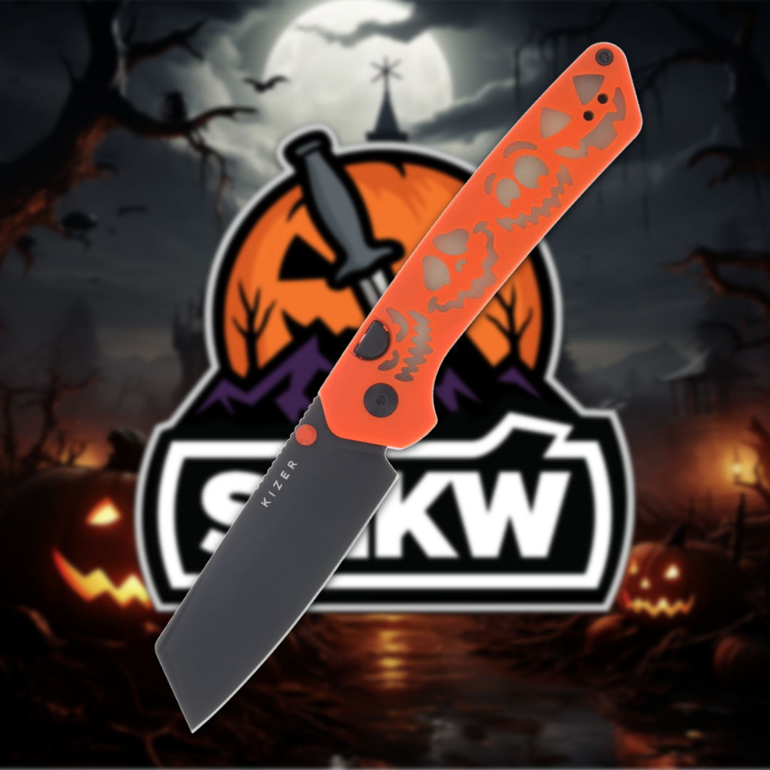 A folding knife with an orange handle featuring skull designs against a dark background.