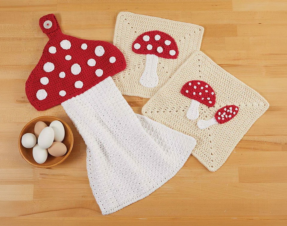 Crocheted mushroom pot holders and dish towel on a wooden surface.