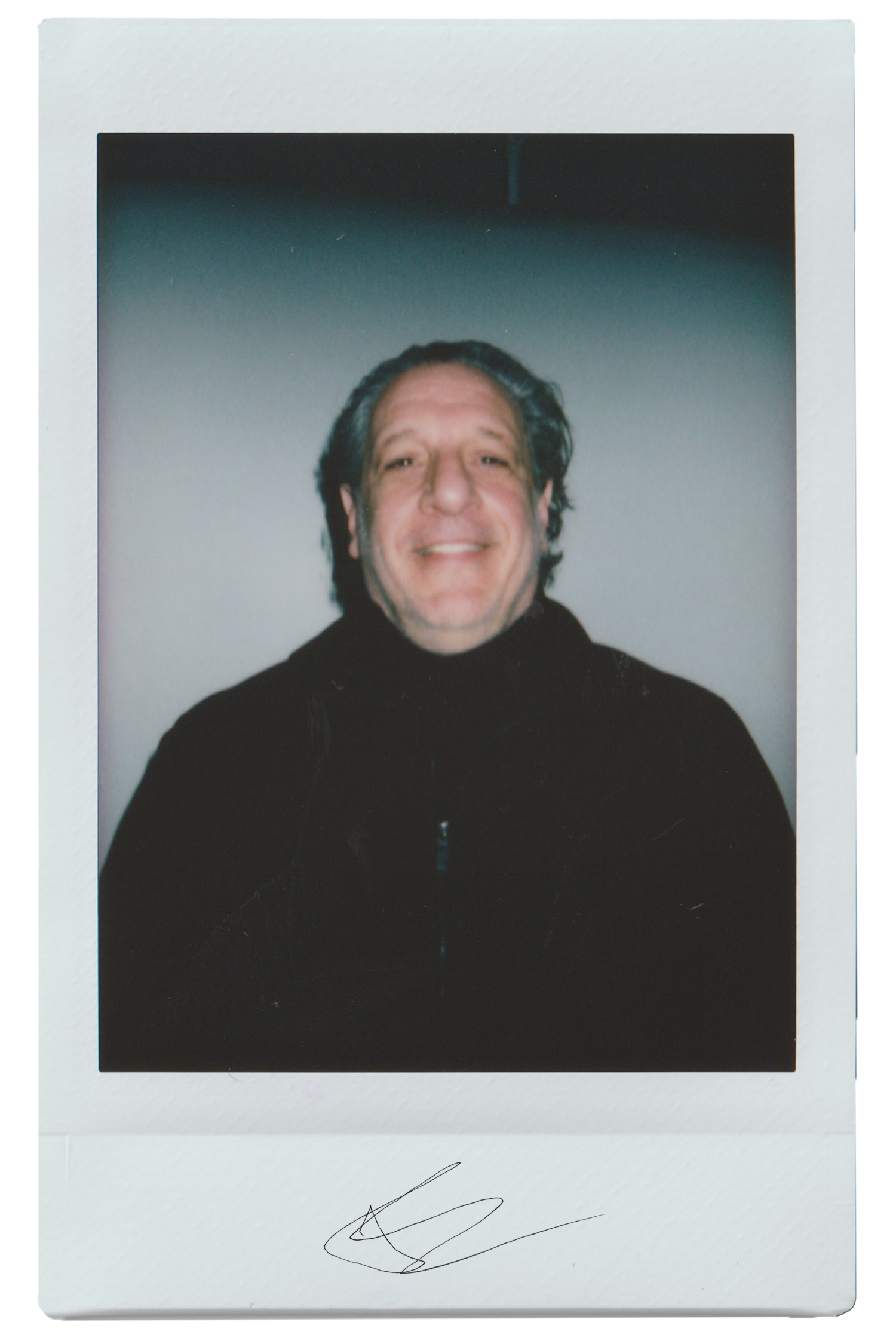 Person smiling in a dark jacket against a plain background.