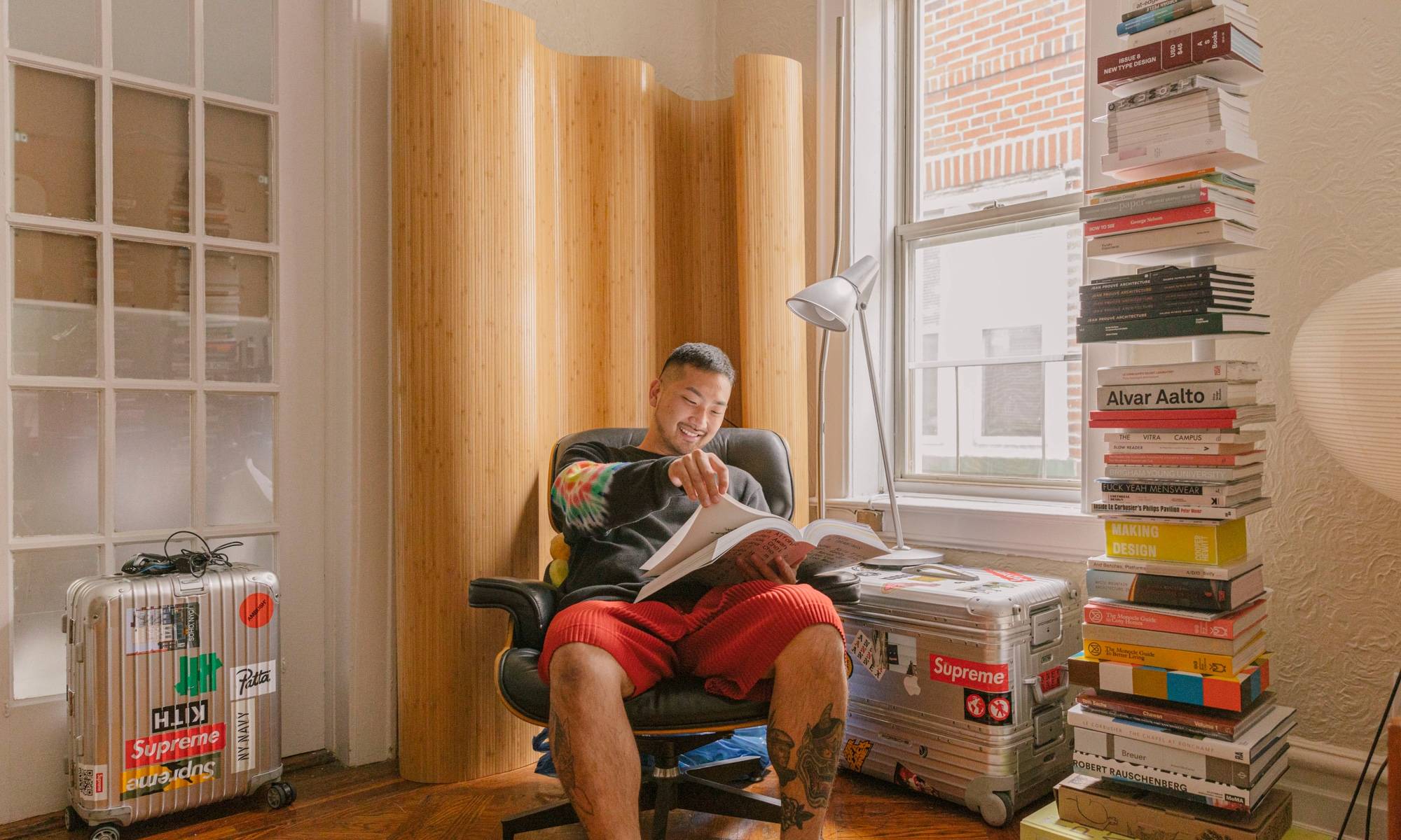  Justin Ryan Kim reading in Herman Miller chair next to stacked bookshelf