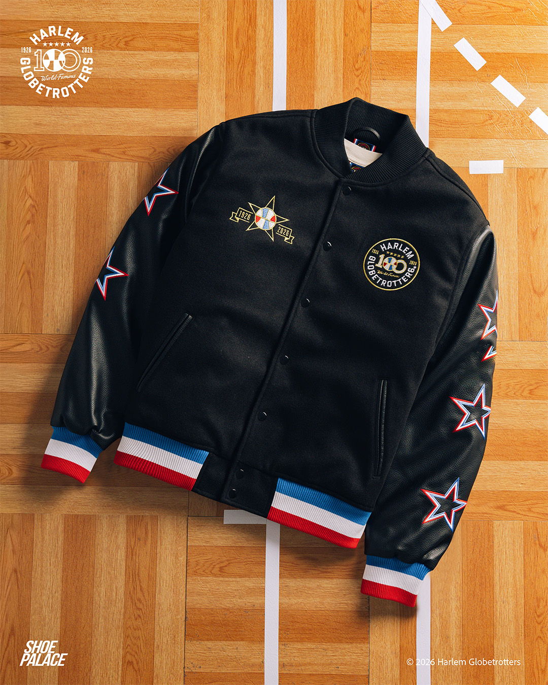 Black varsity jacket with floral and star designs on sleeves.