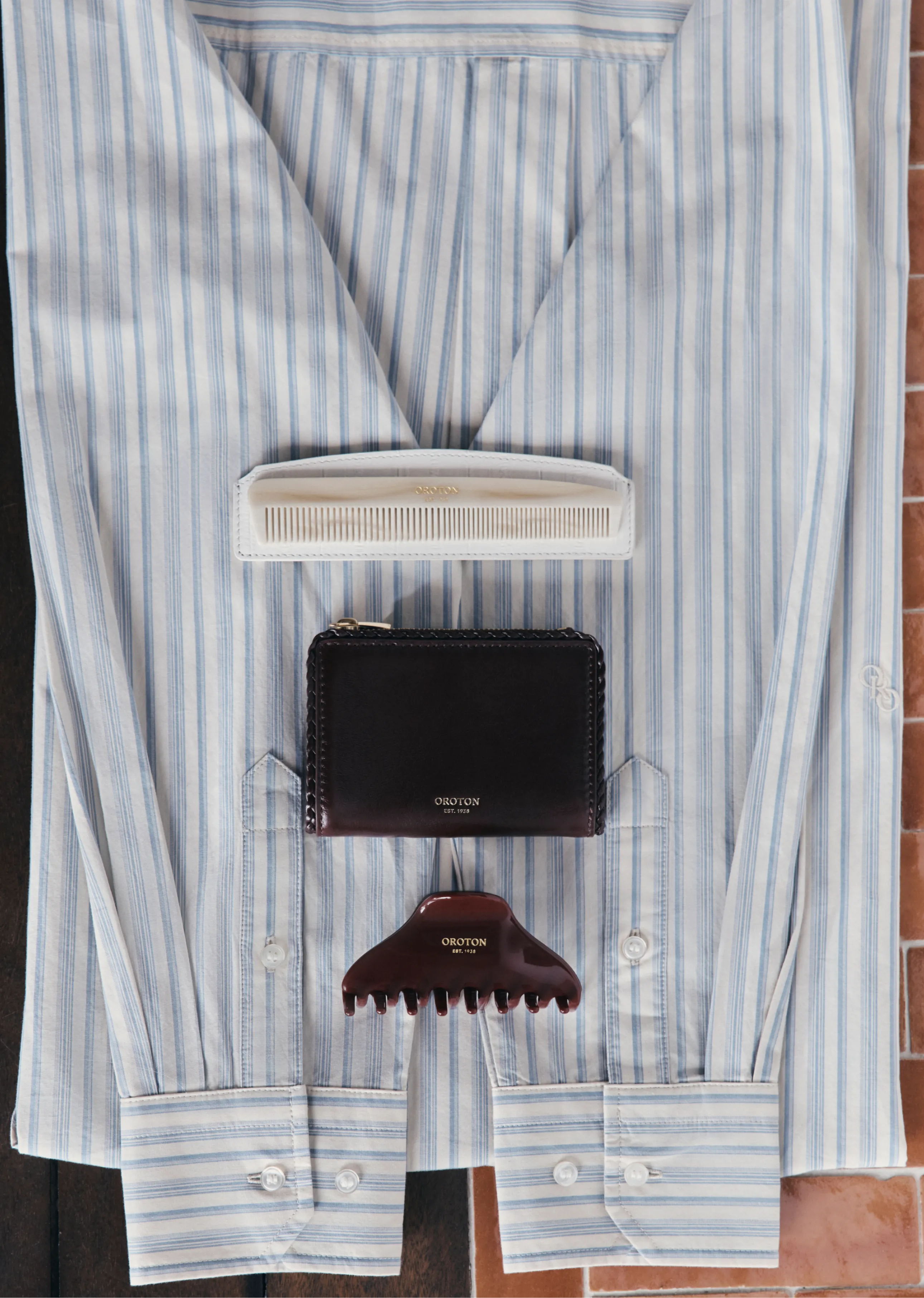 A striped shirt with accessories laid flat on a surface.