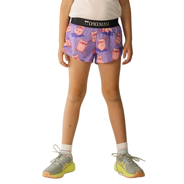 Child wearing purple shorts with a playful design and sneakers.