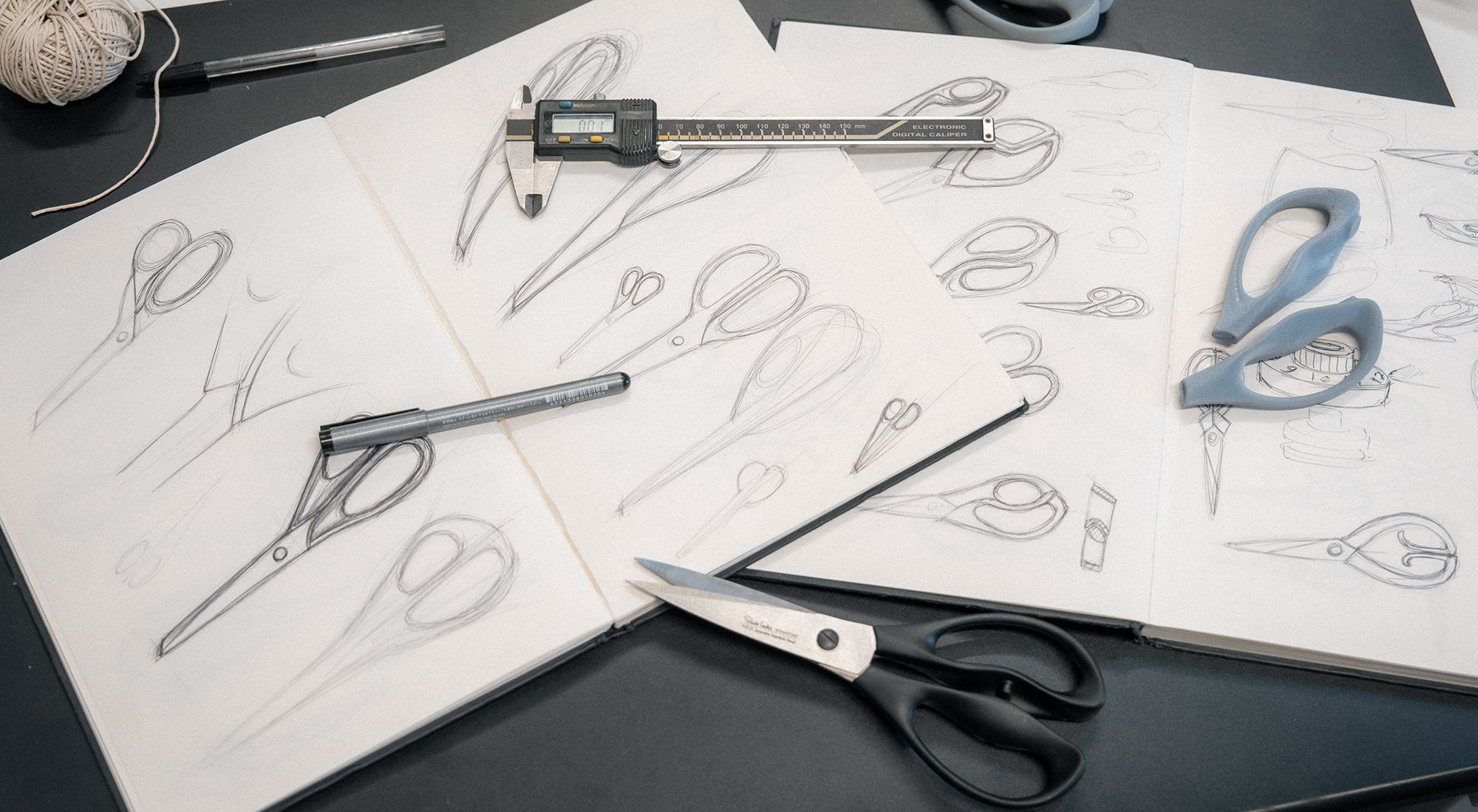 Sketches of Signature Scissors and measurement tools on a table.