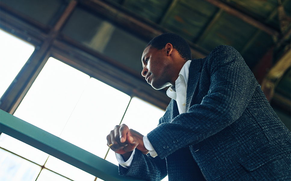 A man in a suit looking pensively out of a window.
