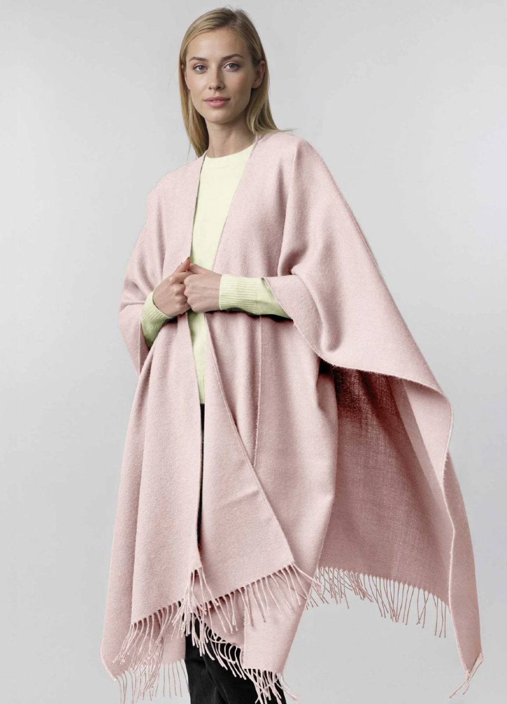 A woman wearing a pink poncho over a light sweater.