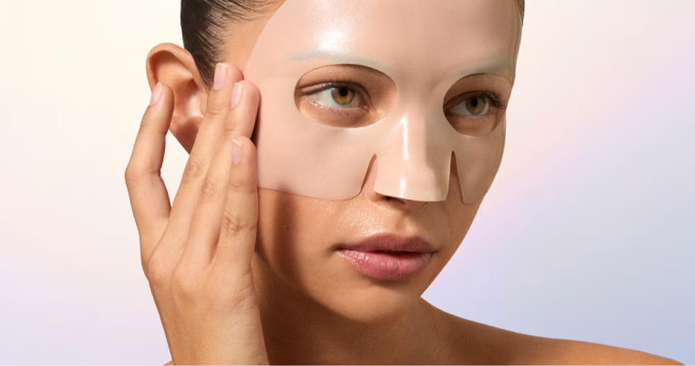 Person applying a facial mask, gently touching their face.
