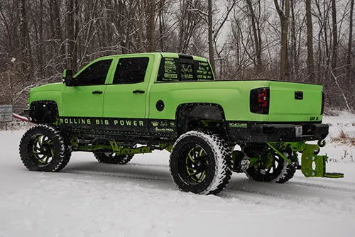 Rear three-quarter view of Joe's bright green 2017 Chevy Silverado 2500HD lifted truck in a snowy setting, install photo 2