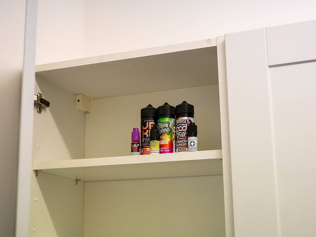 A photo showing vape juice bottles being stored safely in a cupboard.