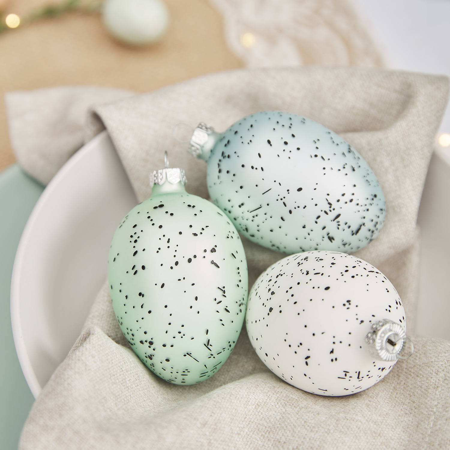 3 blue, white and green egg baubles in a bowl as part of an Easter dining display.