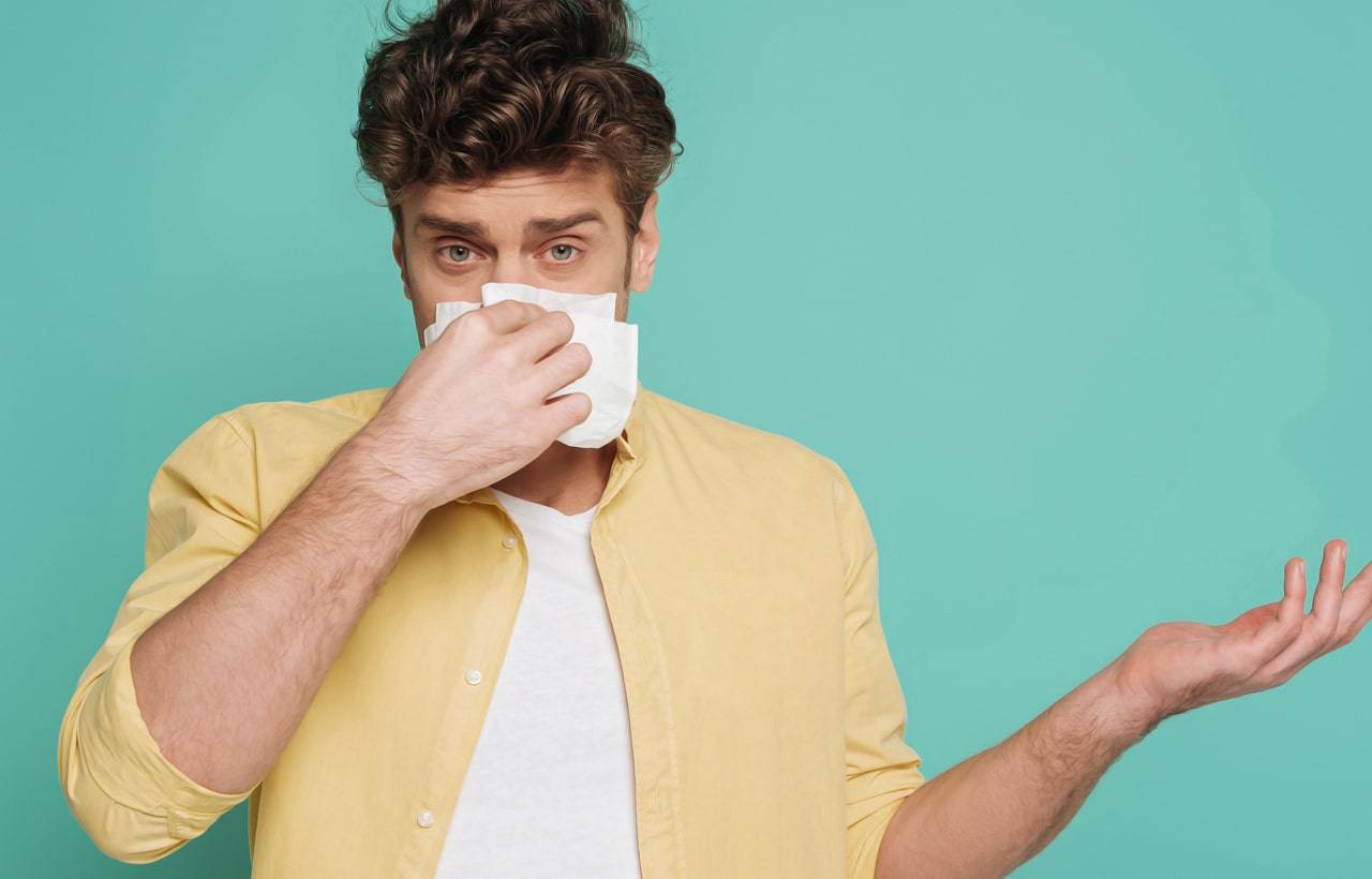 Jeune homme portant un mouchoir à son nez - nous ne pouvons pas bien voir son visage, mais il pourrait souffrir d’une allergie aux graminées. 