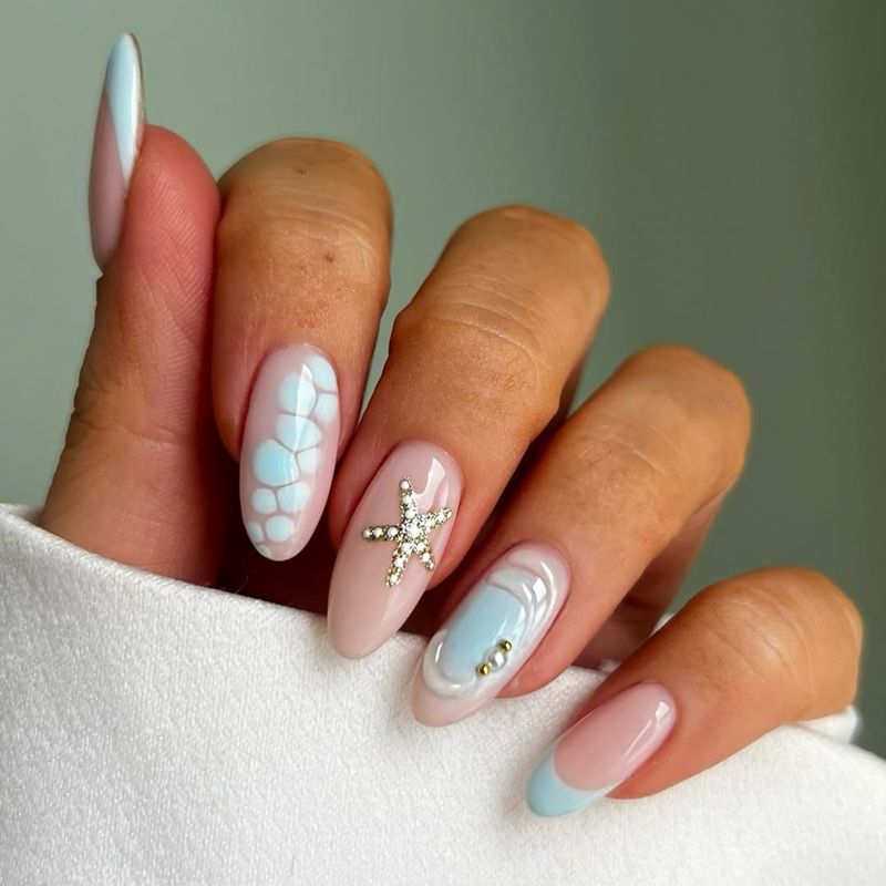 A hand with stylish pastel nail art and decorations.