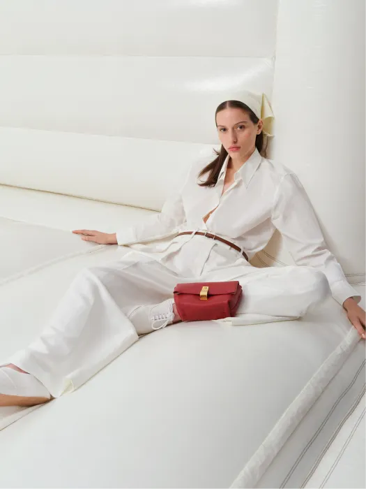 Woman in white outfit sitting on a large, soft white surface.
