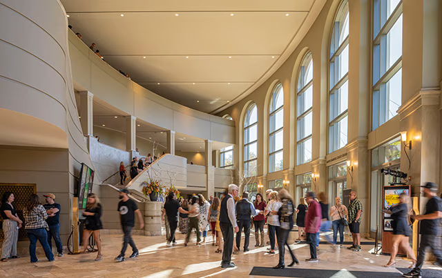 Gallo Center for Performing Arts Lobby AV Crowded lobby with people, large windows, and a staircase.