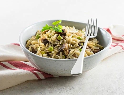 Bowl of orzo pasta with vegetables and a fork on the side.