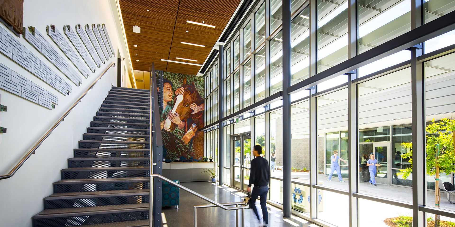 UC Davis Lobby AV Video Wall Interior of a modern building with stairs and large windows.