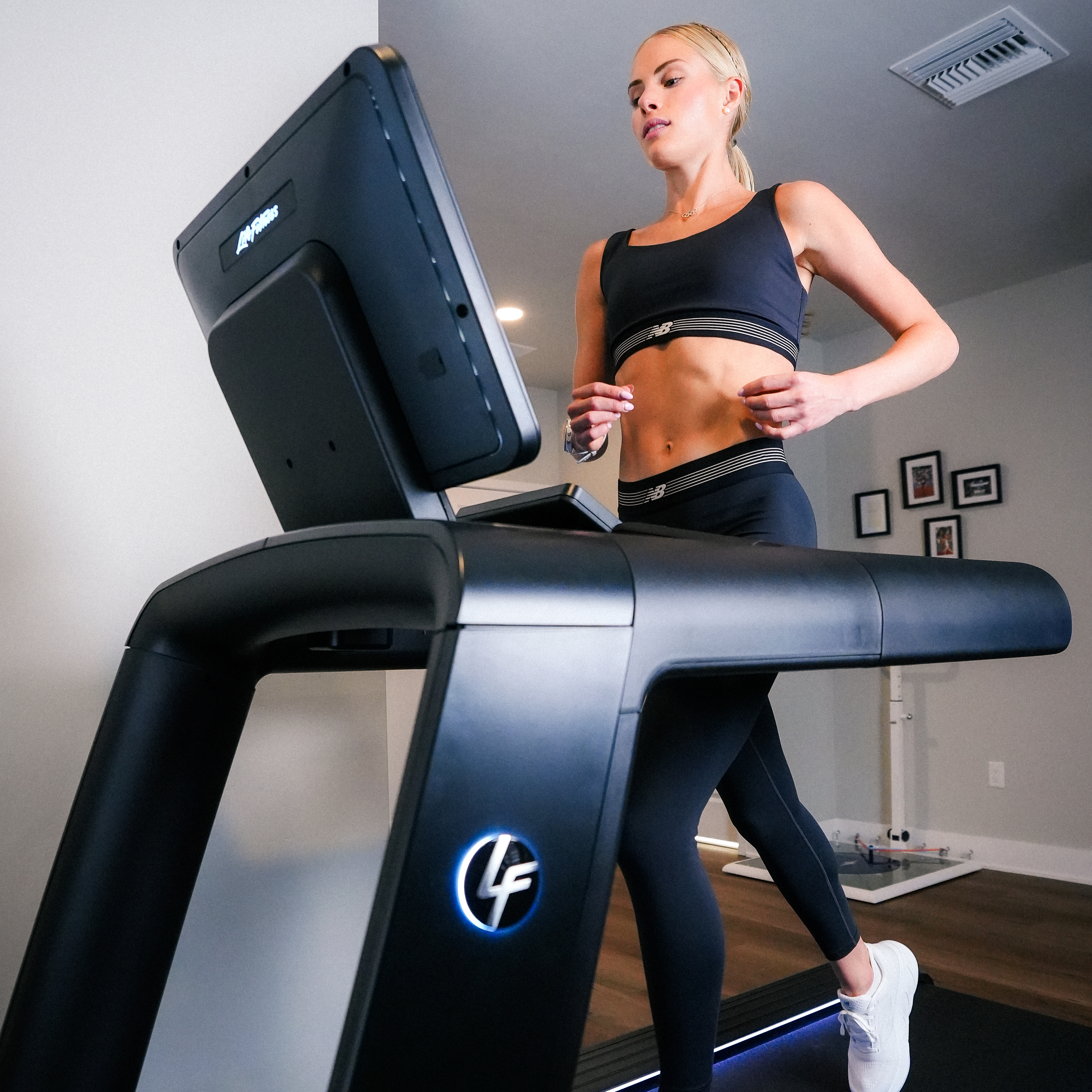 Woman running on a treadmill in a home gym setting.