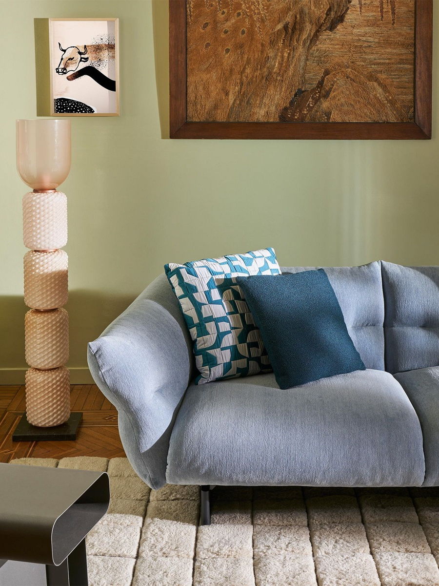 A modern living room with a Cassina sofa, decorative pillows, and art on the walls.