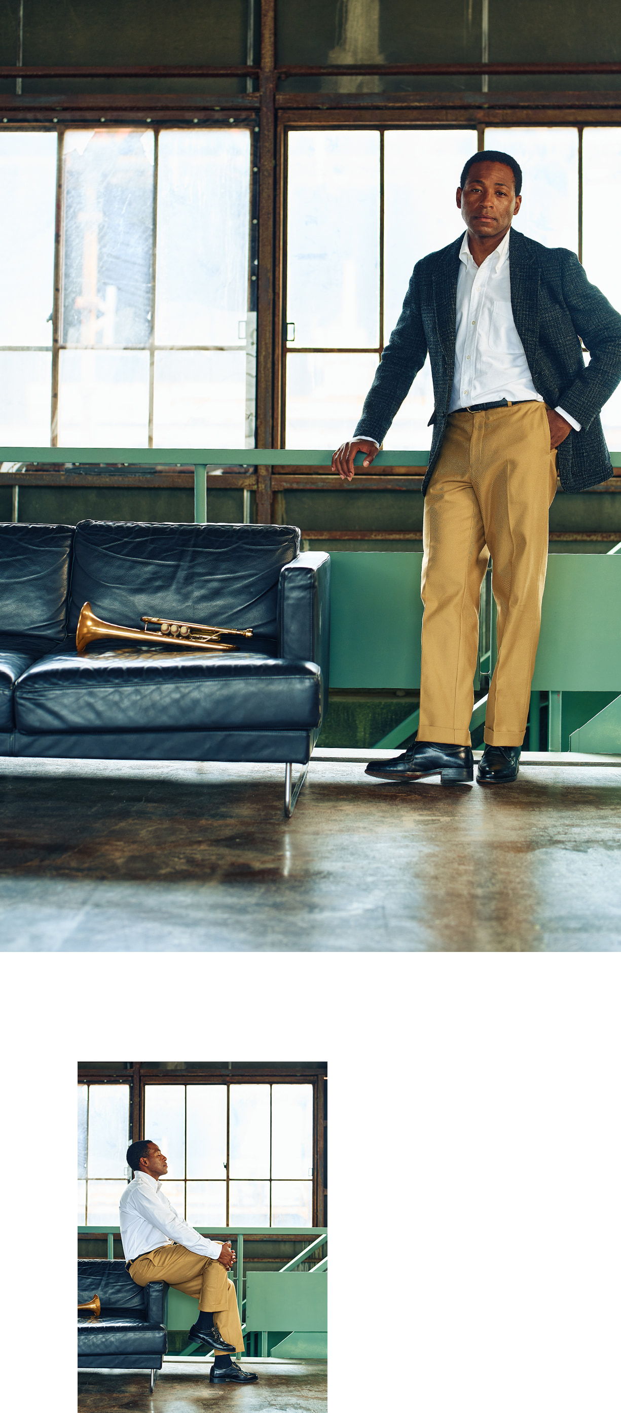 A man in formal attire stands beside a couch with a trumpet.