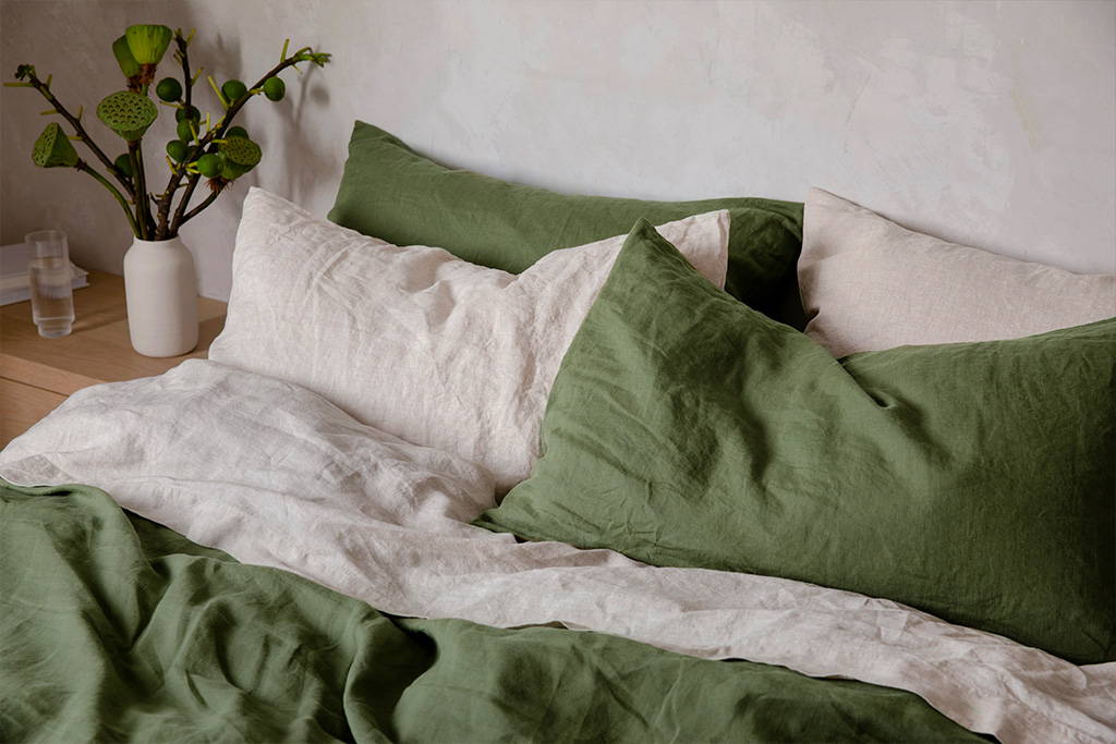 Styled bed with Cultiver linen bedding in Forest and Natural colours. Floral arrangement sits on the bedside table. 