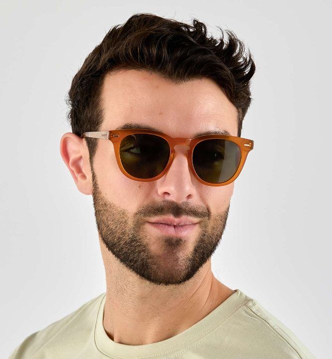man wearing Sunset sunglasses with dark green polarized lenses on a white background