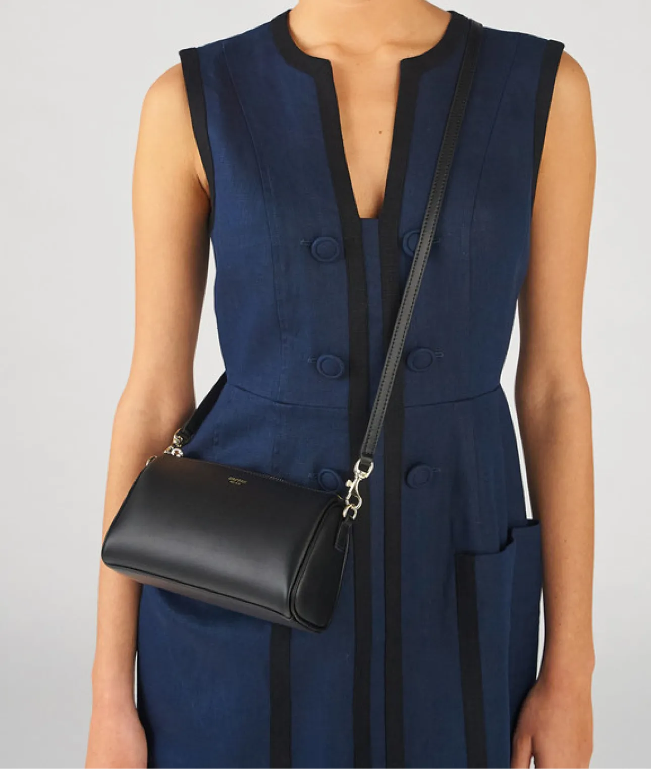A model wearing a navy dress with a black handbag.