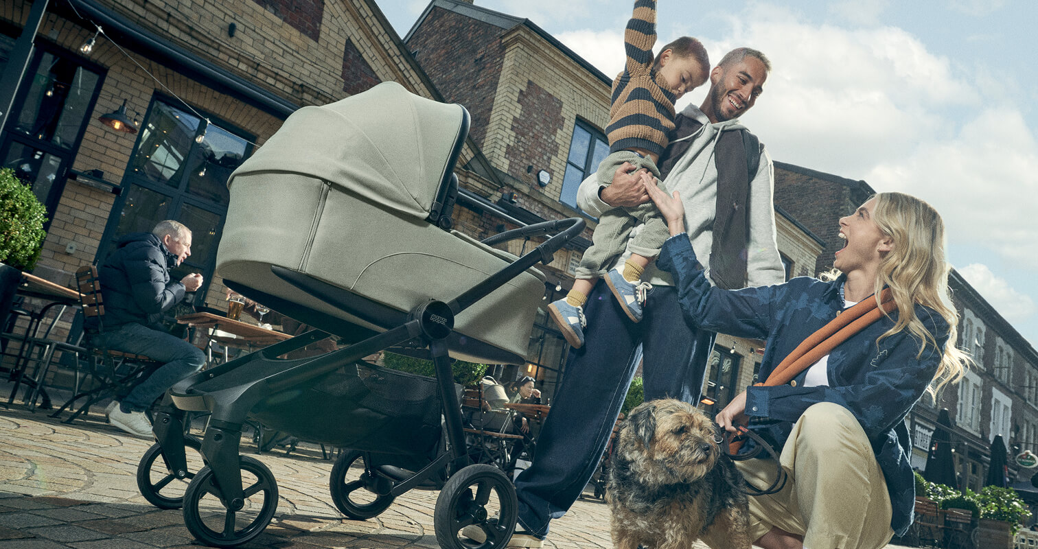 Family with a child in a stroller and a dog outside a café.