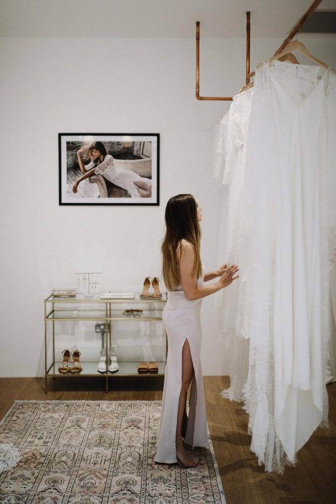 Die Braut betrachtet die Fülle des Kleides von Grace Loves Lace in London