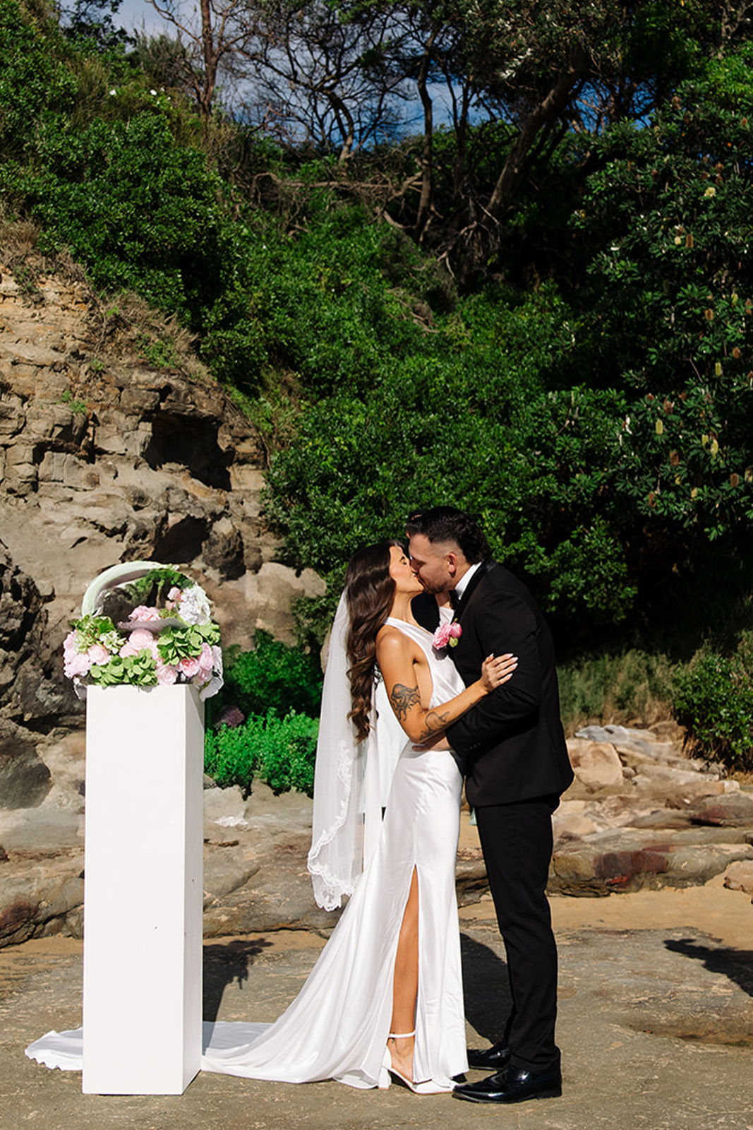 A couple kissing during their wedding ceremony outdoors.