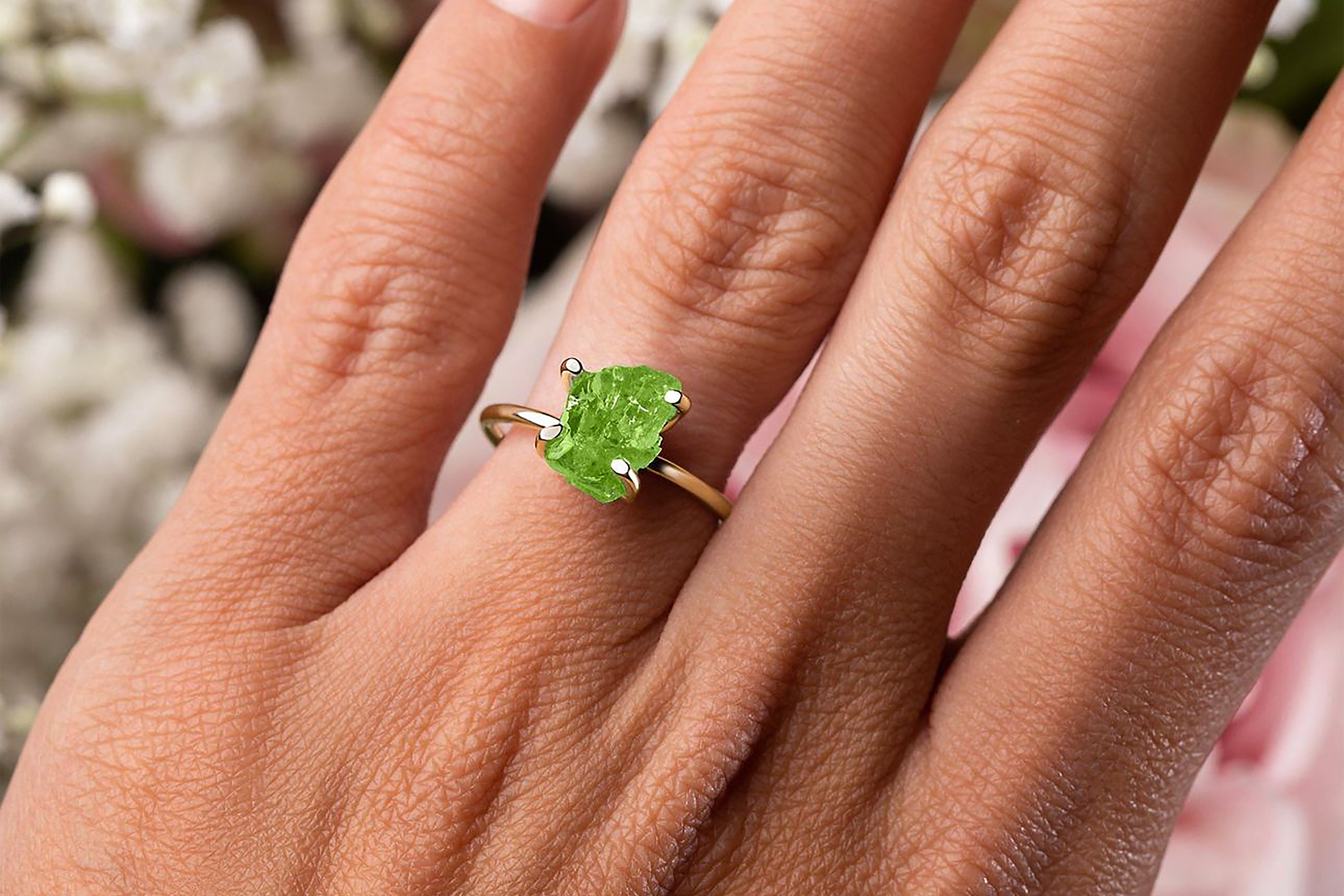 A woman is wearing a Raw Crystal Peridot gemstone ring on her ring finger. 