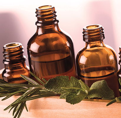 Brown glass bottles on a wooden tray with herbs.