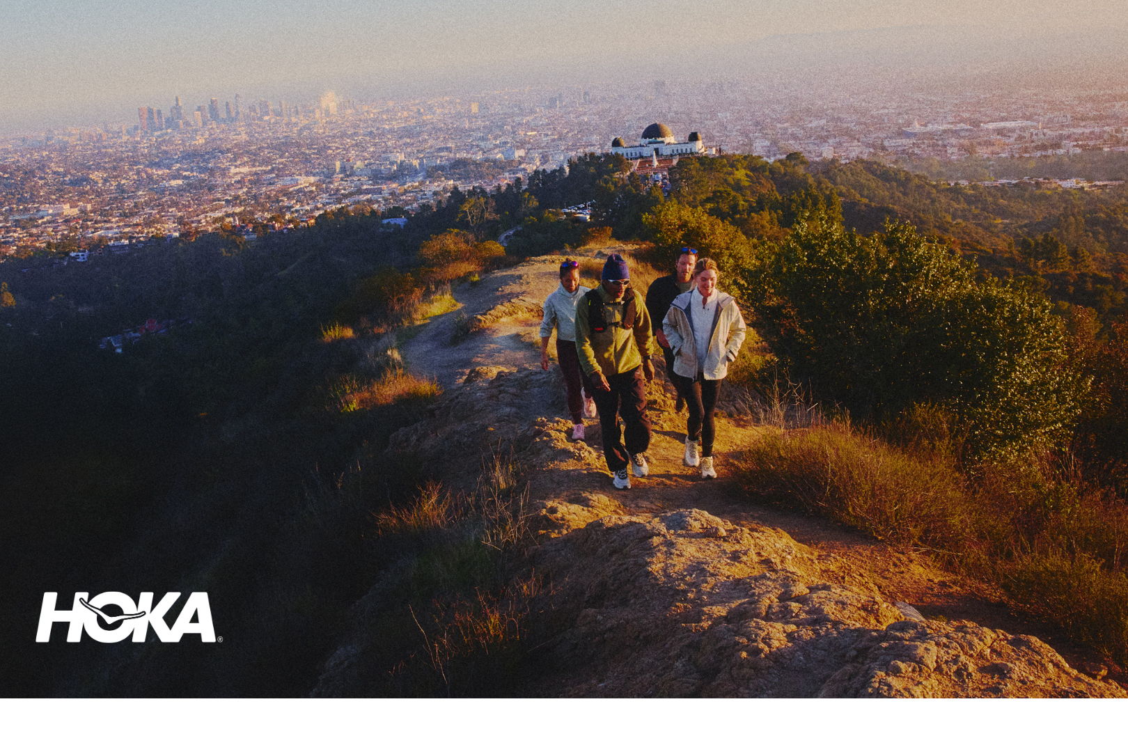 People hiking on a scenic trail with a city view in the background.