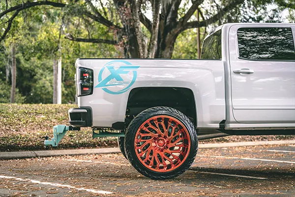 Side profile Nick's lifted Silverado with teal horns and matching drop hitch photo 3