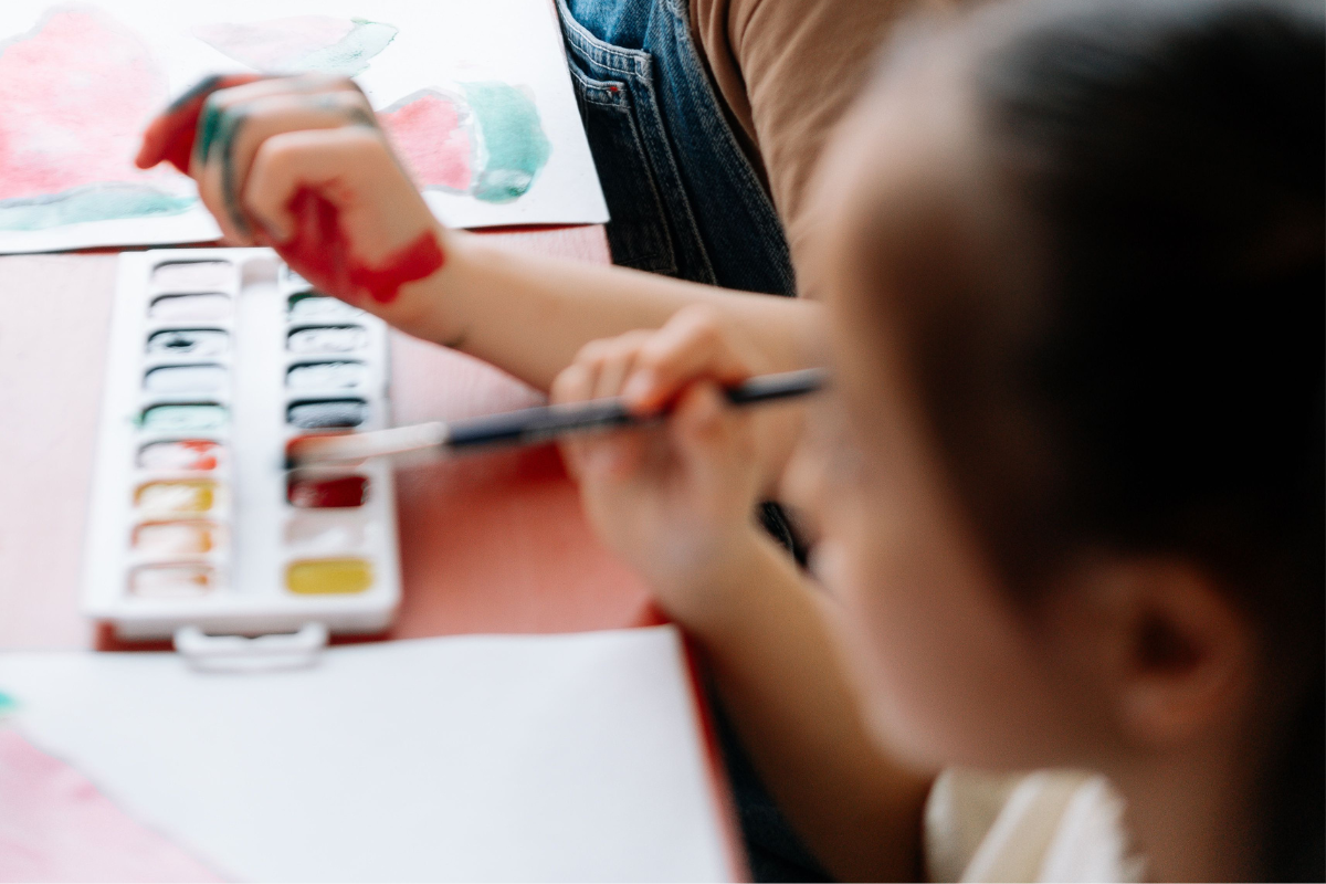 Child painting with watercolors on paper.
