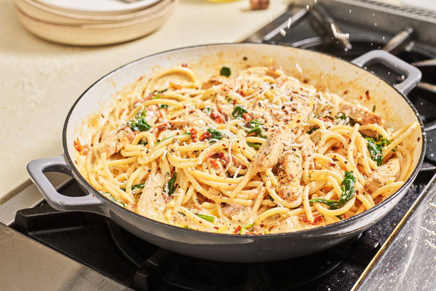 Bucatini pasta, chicken, spinach and sun-dried tomatoes combined in a creamy cheesy sauce prepared in a skillet