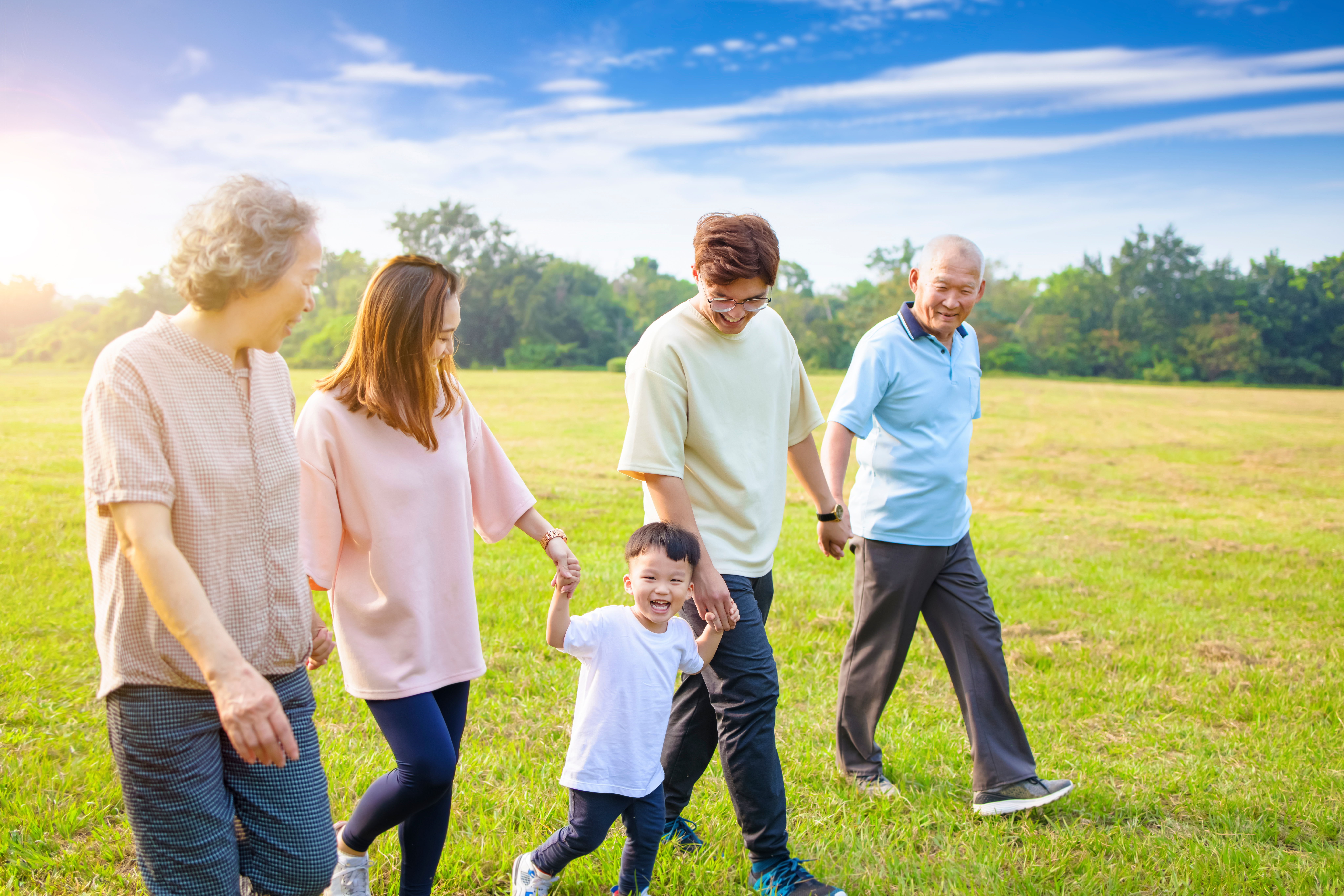 A family walking together in a sunny field, enjoying quality time.