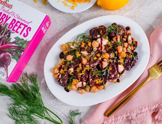 Colorful salad with beets, chickpeas, and herbs on a white plate.