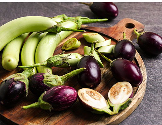 Fresh green and purple vegetables on a wooden cutting board.