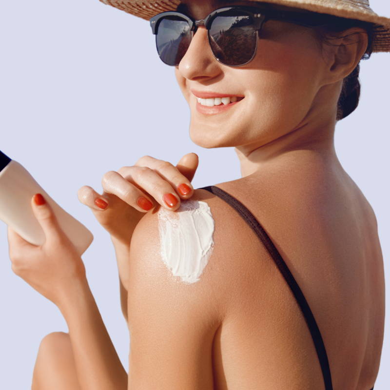 A woman wearing sunglasses rubs sunscreen onto her shoulder