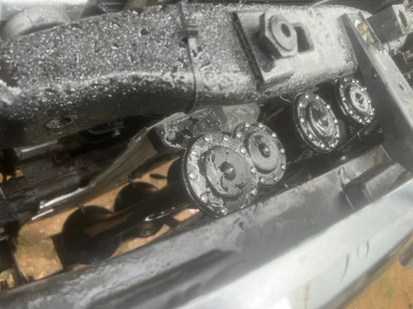 Close-up of four black circular horns mounted in row behind front bumper covered in water droplets