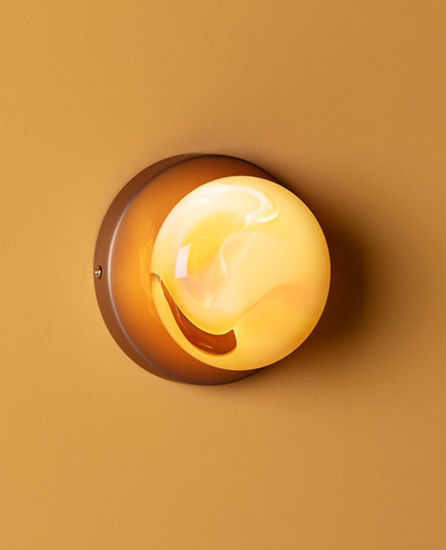 Round orange lamp mounted on a brown wall.