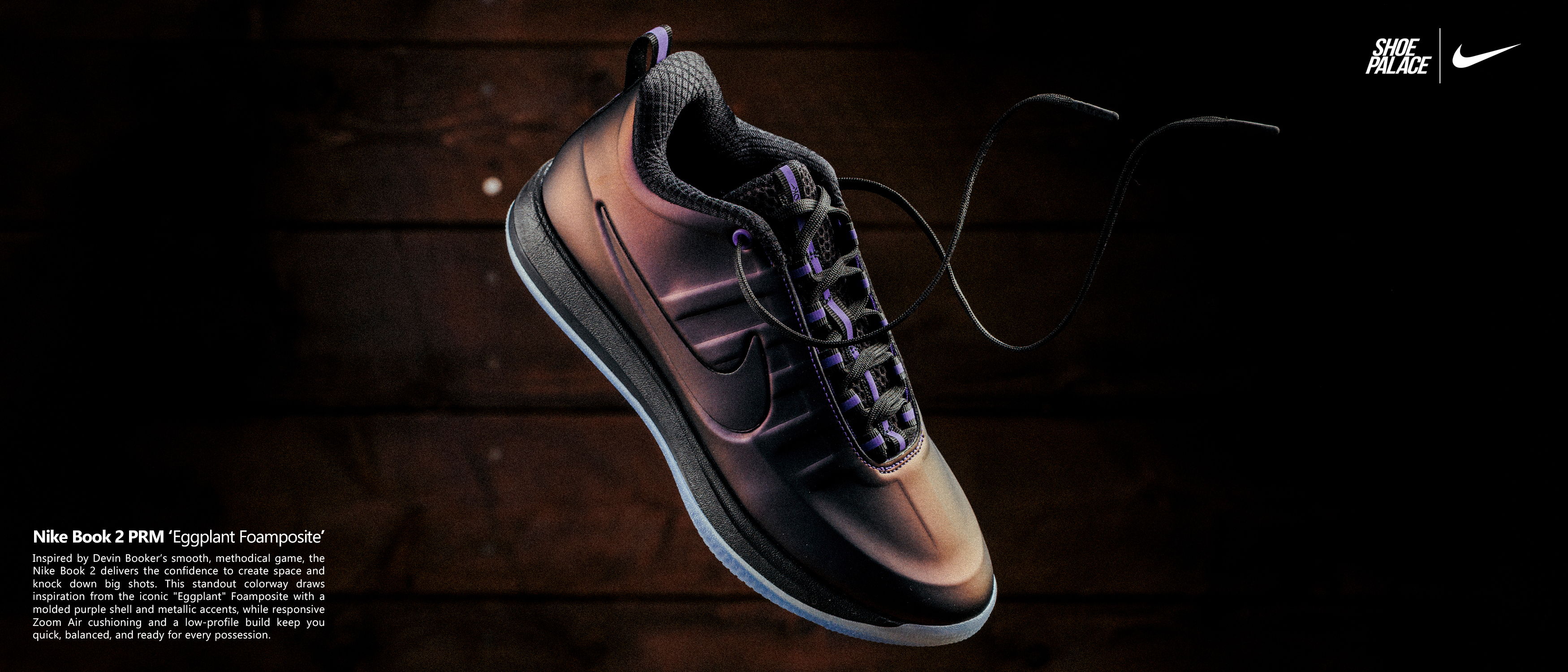 Black athletic shoe with laces on a dark wooden surface.